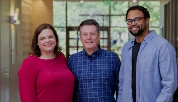 Three people stood together smiling at camera